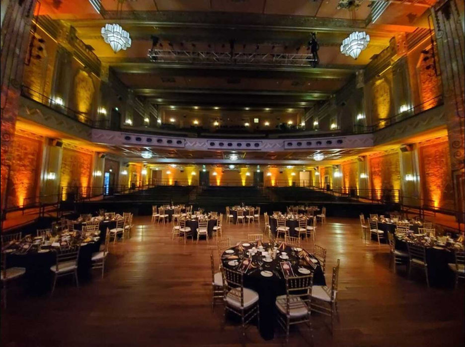 several round banquet tables, fully set, on the main floor of the Fox Theater in Pomona, with no people