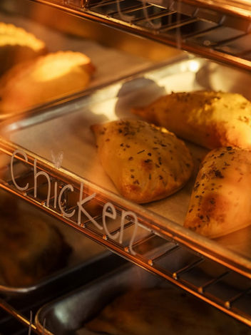 Golden "Chicken" empanadas baking on a sheet in a hot oven.