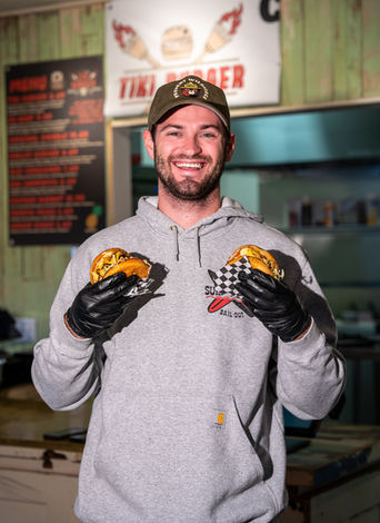 Smiling man holding two Tiki Burger patties