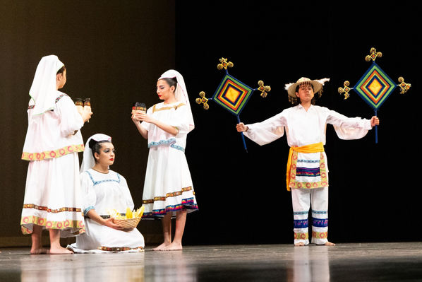 Children in traditional Mexican attire perform on stage for La Gran Posada