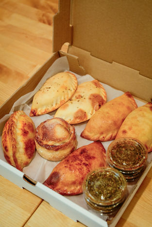 Assorted empanadas in a box with two sauces