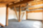 interior view of open wooden rafter ceiling loft space in #9 Wurl Building with ample sunshine pouring in, white walls, and tiled industrial carpet, windows, etc.