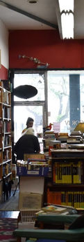 Person sits in bookstore aisle; bookshelves full of books