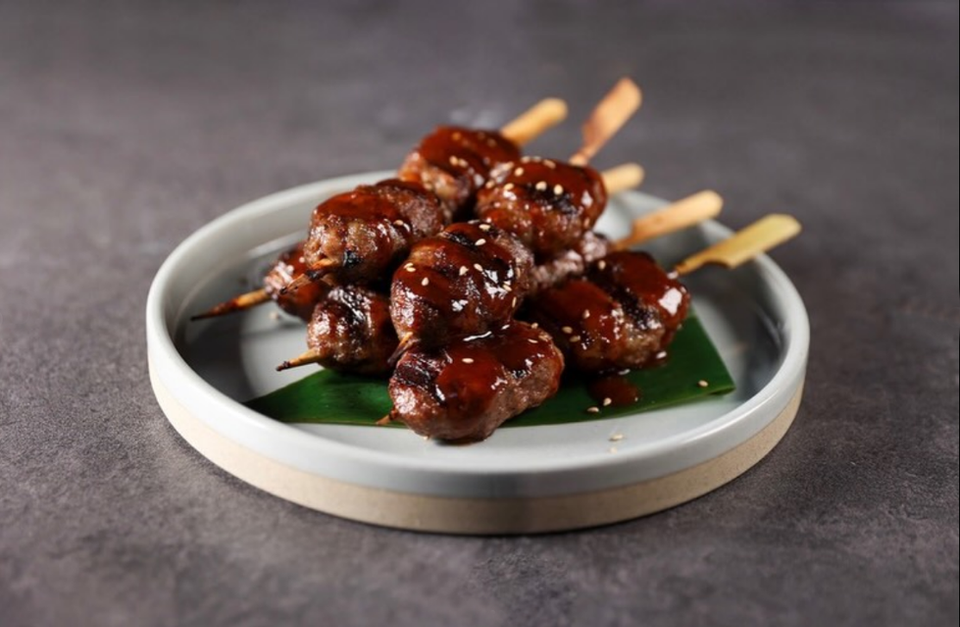 Glossy yakitori skewers with dark sauce and white sesame seeds.