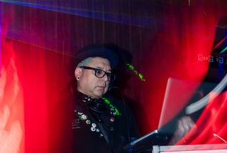 DJ playing music at a nightclub, with equipment and red lights Flyway Bar+Nightclub