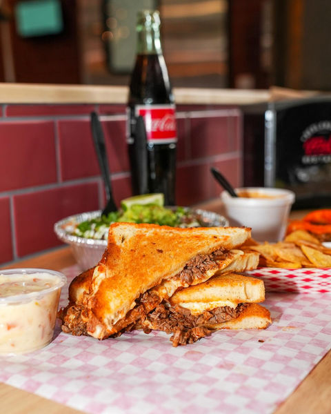 Grilled cheese sandwich and side dishes with Coca-Cola bottle and a meal