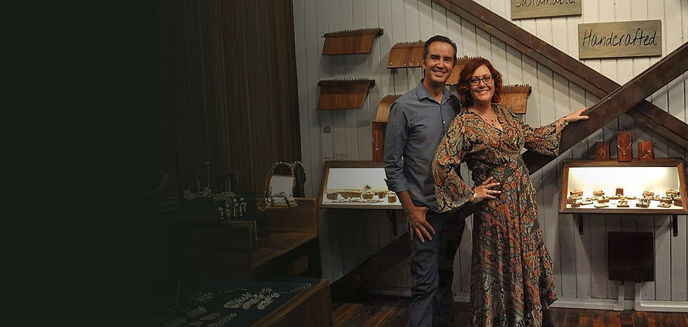 Kevin & Heather smiling, pointing at "Handcrafted" sign in custom shop.
