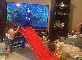 2 children watching Ms Raven on a TV