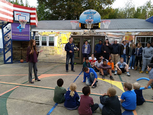 Woman speaking to a group of people on a basketball court