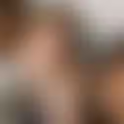 A group of young friends sits close together, smiling and enjoying each other's company against a concrete wall.