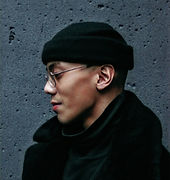A man with a beanie on and glasses showing a side profile.