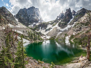 Emerald green alpine lake. snow capped mountains in the background on a cloudy day.