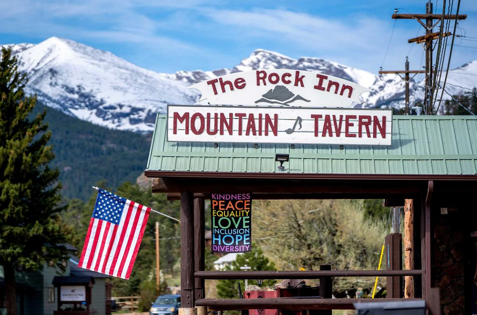 Rock Inn Mountain Tavern entrance with snow capped mountains in the background.