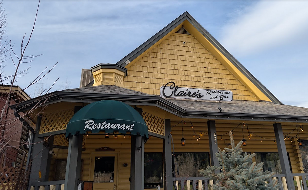 Exterior of Claire’s Restaurant and Bar, a yellow building with a green awning, porch lights, and a calm sky above.