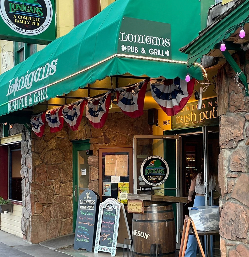 Green awning at Lonigans Irish Pub & Grill with patriotic bunting, menu boards, and open doorway in a lively pub entrance