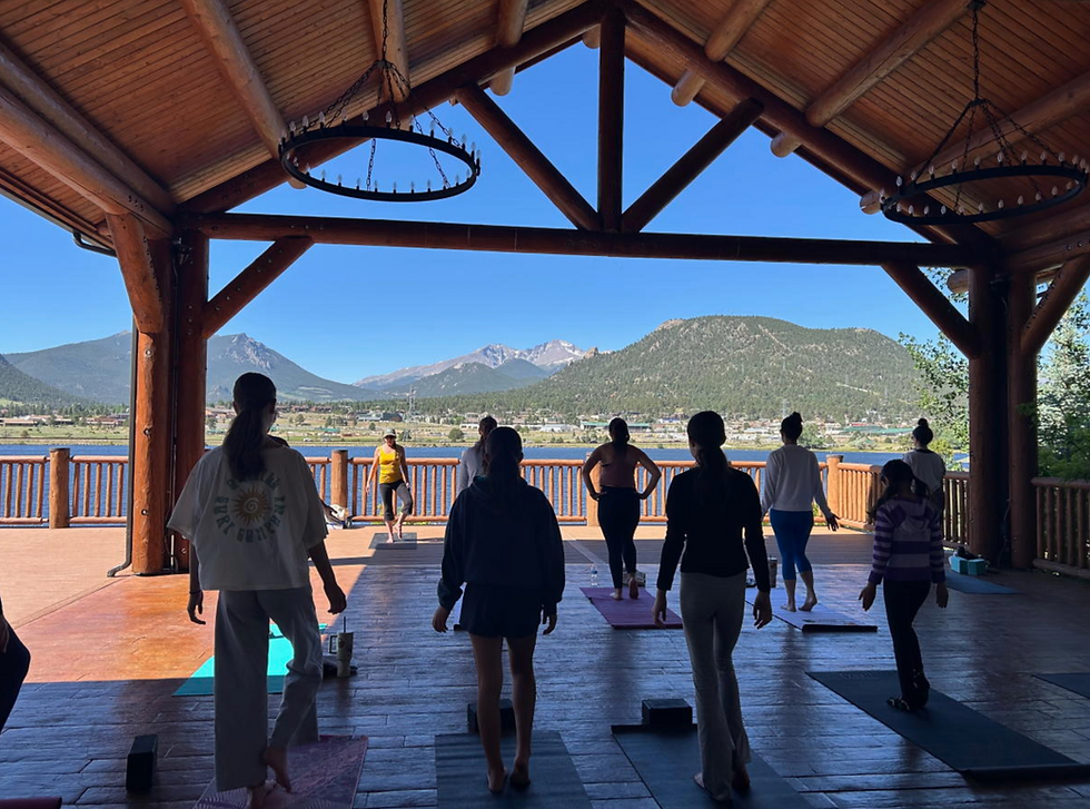 Wooden Pavilion with a yoga class and mountains in the distance.