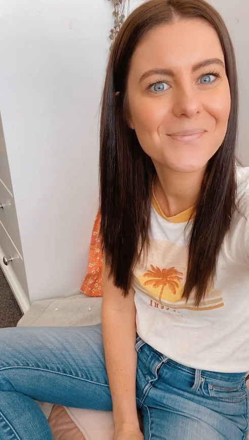 Photo of Tayte sitting in a cosy corner in a relaxed t-shirt and jeans, smiling