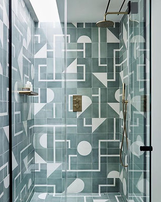 A modern luxury shower with walls and floor clad in a tile that features a bold, graphic pattern.