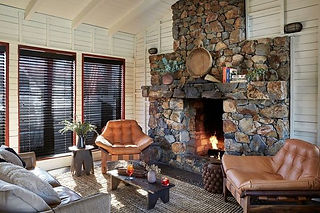 Seating cozied up to a stone fireplace, books stacked on the hearth, and live plants decorating this space look more like a private home than the commercial hospitality space it actually is!