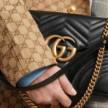 Hand holding a black Gucci Marmont bag