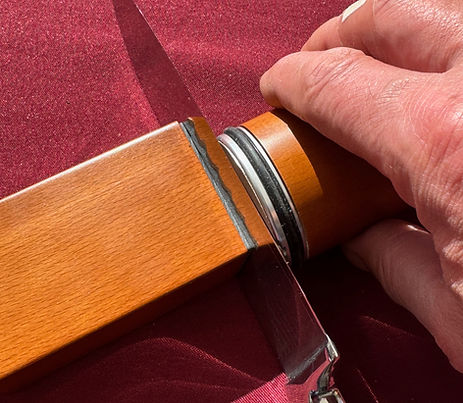Messer schleifen mit dem Rollschleifer – die Hand führt den Rollschleifer entlang der Klinge, die an der magnetischen Basis fixiert ist