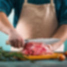 Kochmesser beim Schneiden von Fleisch auf Holzbrett in der Küche