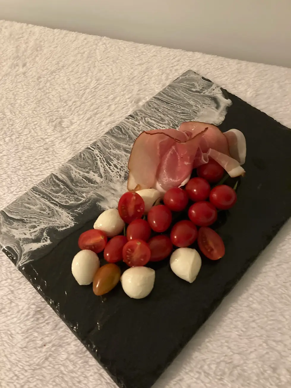 Miniaturbild: Antipasti-Platte aus Schiefer mit Trauben, Käse und Aufschnitt – Ansicht von oben in Studio-Setting