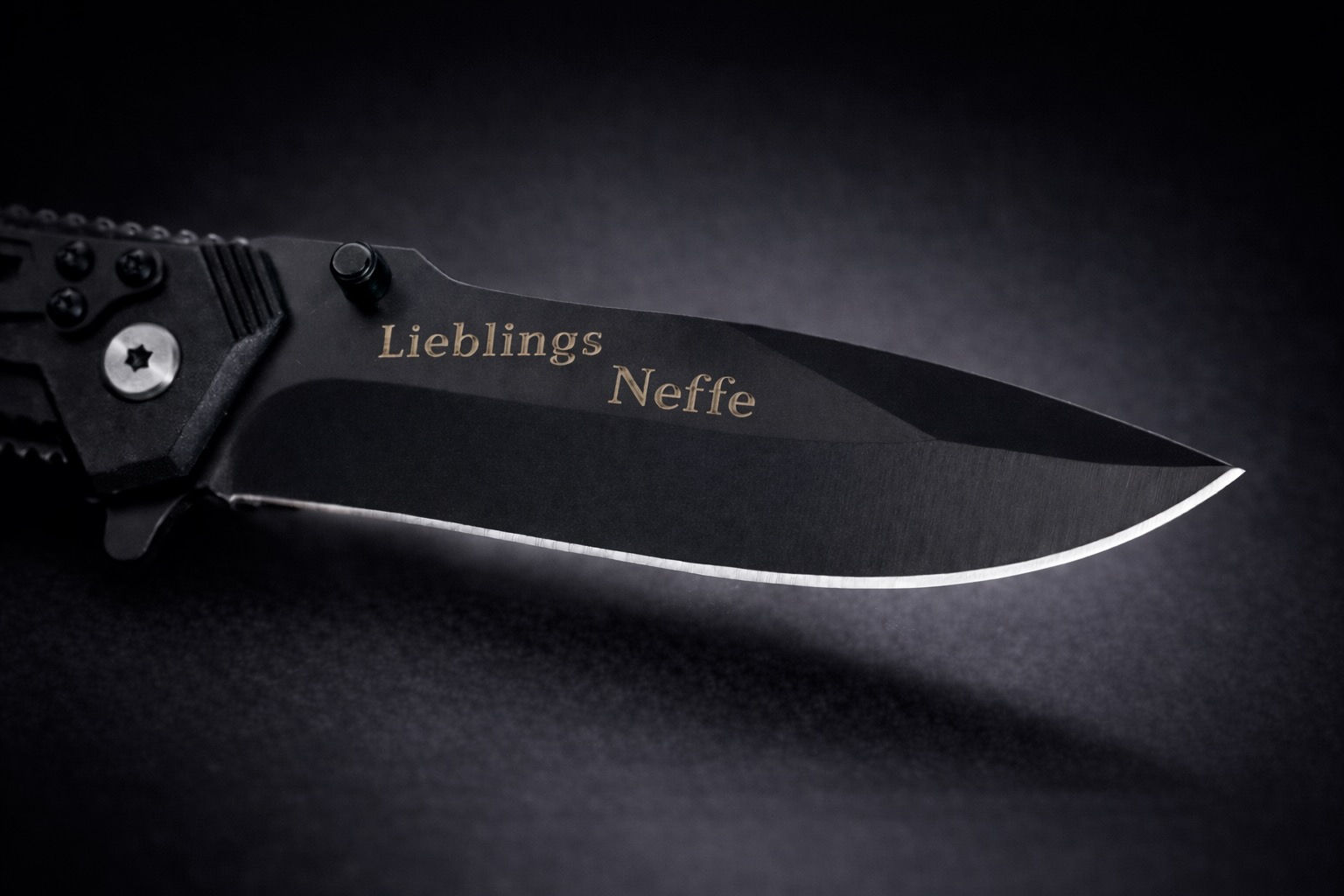 Schwarzes Taschenmesser mit Gravur „LieblingsNeffe“ auf der Edelstahlklinge. Das Messer liegt auf dunklem Hintergrund