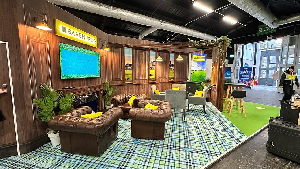 Barenbrug's brand space at BTME, which is fashioned to look like a golf clubhouse. It has wood panelled walls, a chequered carpet and leather lounge chairs, with a TV on the window, and golf grass in the corner.
