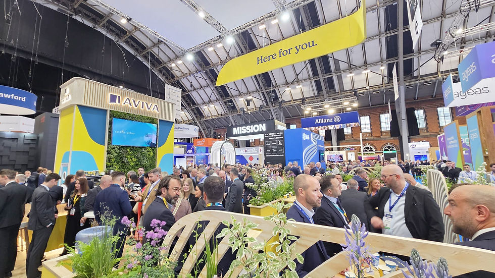 A busy exhibition stand, with 'Aviva' written at the top of it. There are lots of people in suits filling the stand and chatting.
