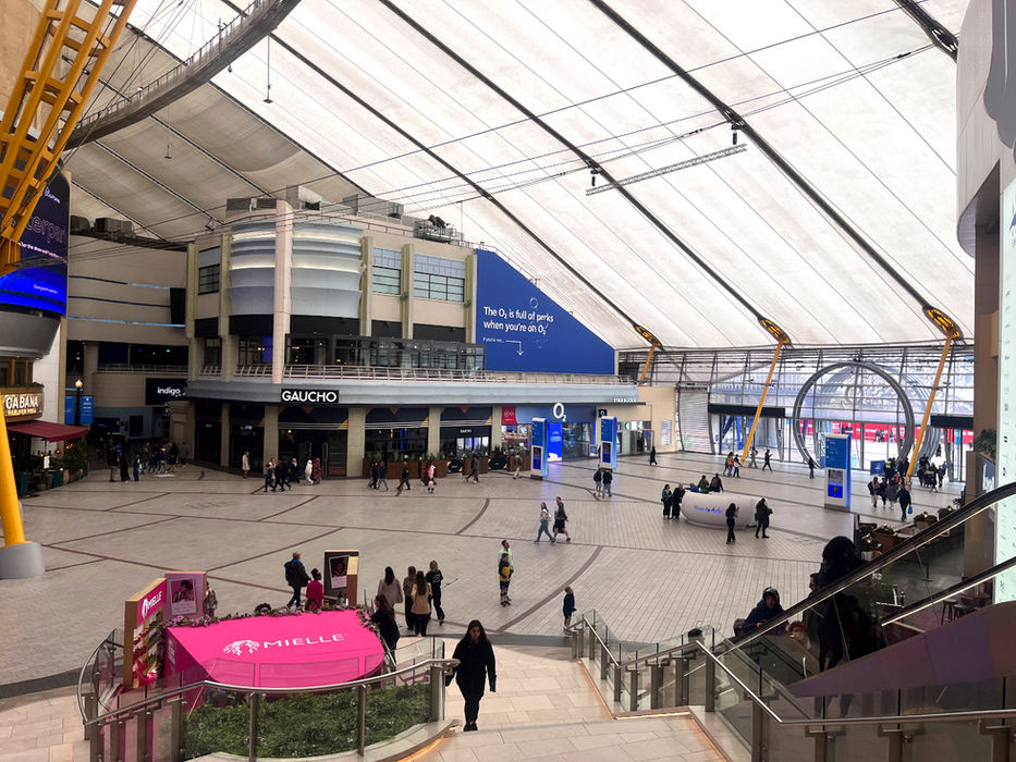 The inside of the O2 building in London, taken from the top of the golden staircase. At the bottom, a bright pink brand space for haircare brand Mielle Organics can be seen.