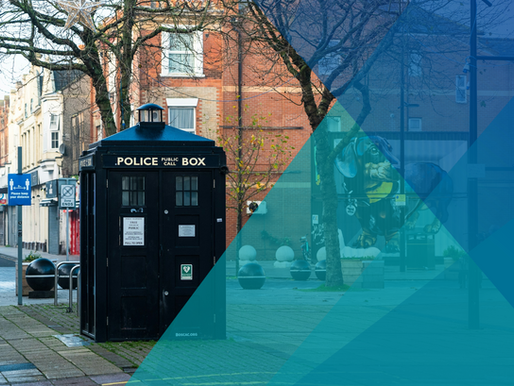 A blue police call box, like a TARDIS, on a brick street, a large dog mural in the background. The right side of the photograph is partially obscured by low opacity blue triangles, representing Image Experiential