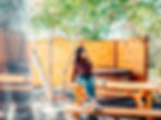 Relaxed individual at a wooden picnic table outdoors, near a covered hot tub, in a private, string-l