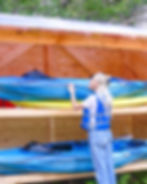 Woman preparing kayak at RnR Glamping, surrounded by greenery, ready for a water adventure.
