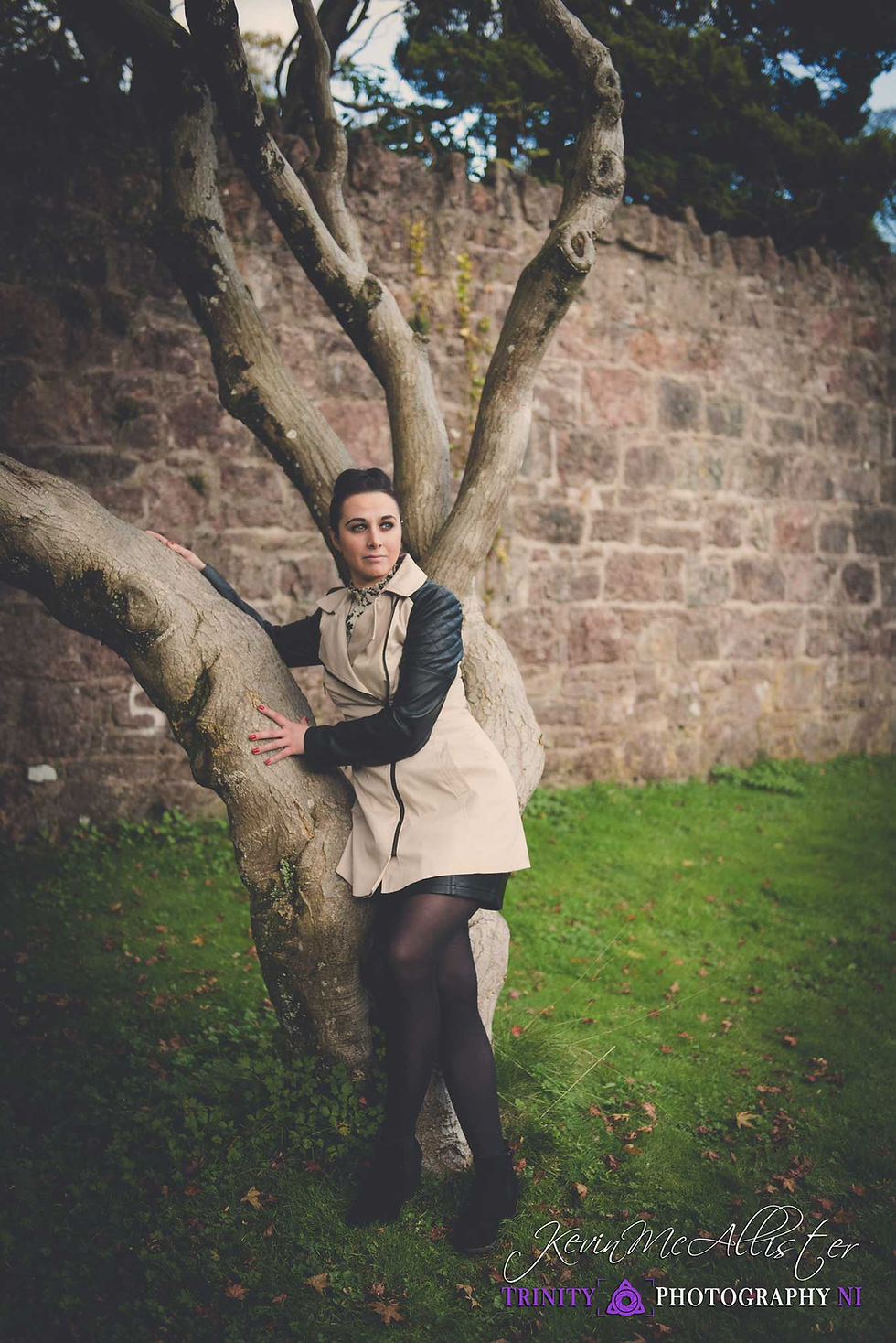 model leaning against a tree with cream Jacket