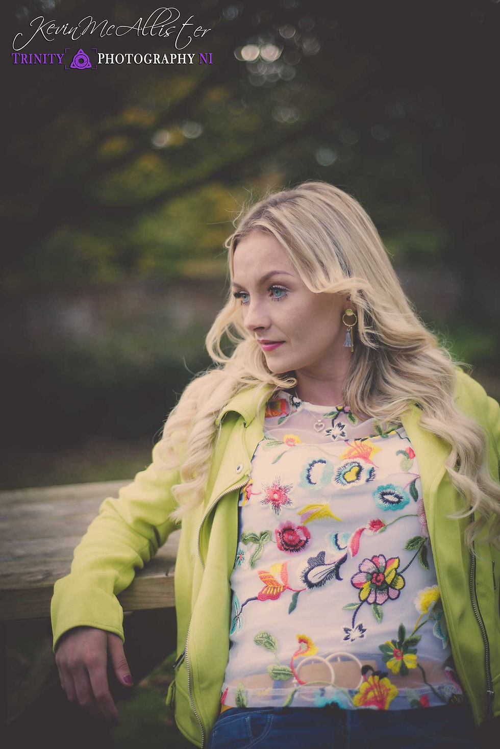 blonde girl green jacket with arm on park bench