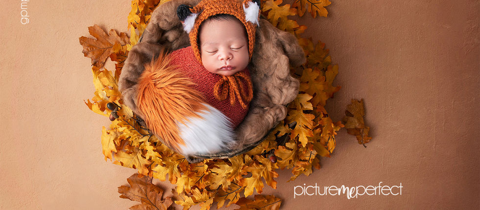Sleeping newborn wrapped in a handmade fox bonnet and tail surrounded by woodland-inspired styling during a luxury newborn photography session.
