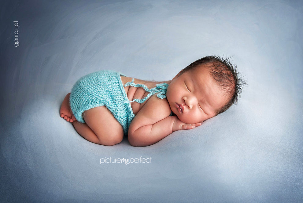 Newborn baby boy sleeping in blue outfit with baby blue fabric backdrop . Miami The Ridges photo shoot