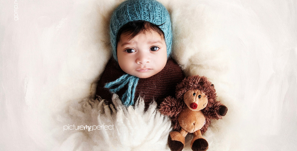 Awake newborn in a teal knit hat with a plush hedgehog toy, At his home in Miami , Windmill Ranch Estates