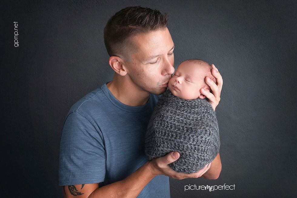Father kissing his newborn baby's forehead during a professional newborn photography session in Miami.