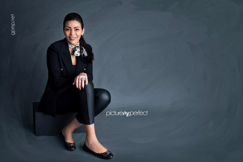 Smiling woman in black blazer, scarf, and pants. The Anchorage photo shoot at her office