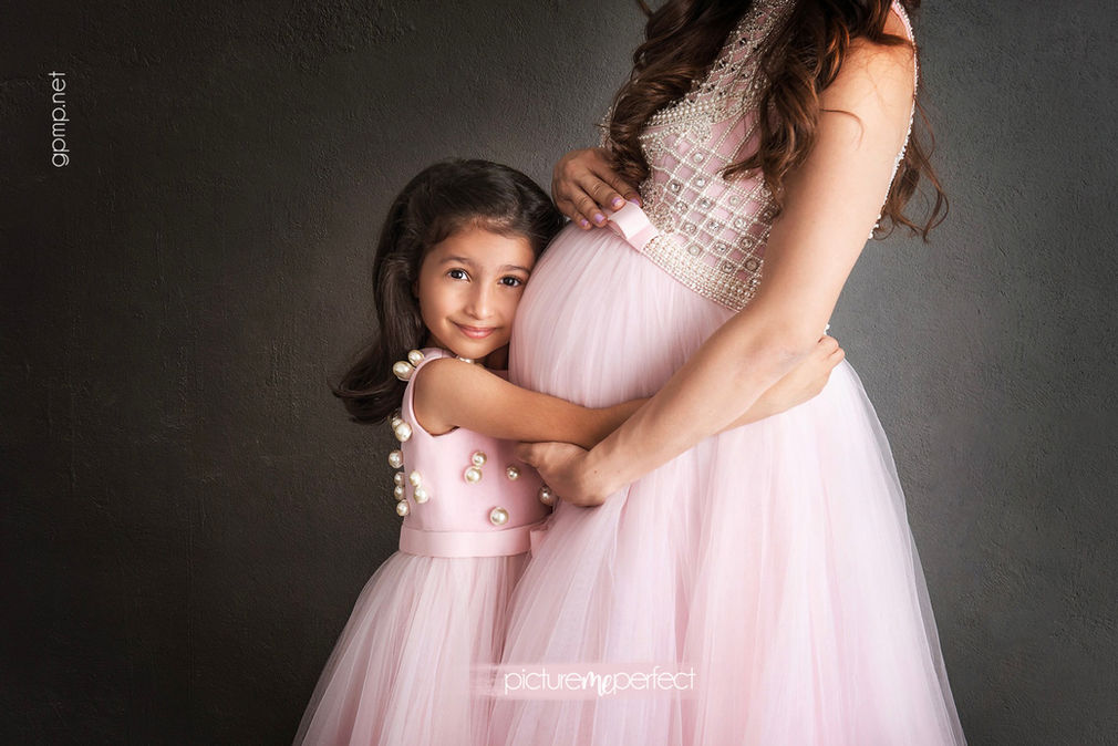 Maternity photo of a young girl hugging her pregnant belly, pink tutu dresses. Photo shoot Weston Hills