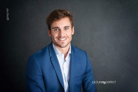Professional portrait of a smiling man in a blue suit.At his office photo shoot in Miami , Laguna Springs