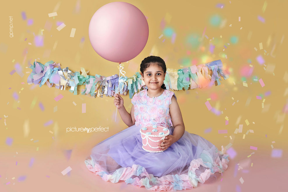 Young girl celebrating with a balloon and cake smash.