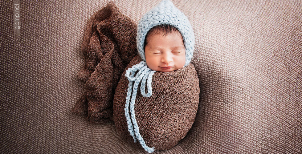 Sleeping newborn swaddled in brown with a blue knit hat. In-Home photo shoot at Miami , Savanna