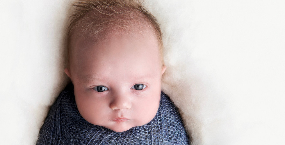 Awake, curious newborn baby swaddled in a blue knit wrap. At his home in Miami , The Ridges
