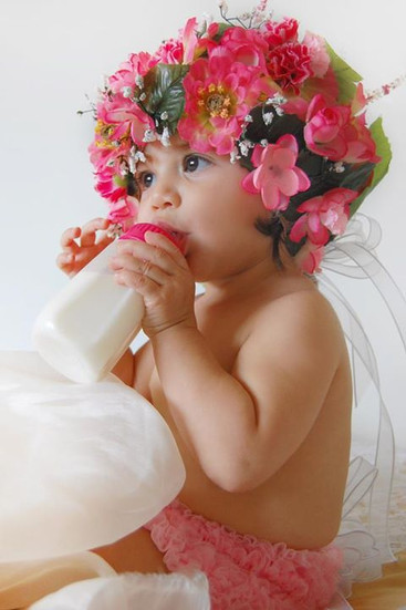 Awake newborn wearing a pink flower crown holding a bottle. In-Home photo shoot at Miami , Emerald Estates