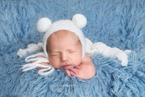 Sleeping newborn in a white bear hat on blue faux fur flokati, In-Home photo session at Miami, Coral Gables,Granada Golf Course area