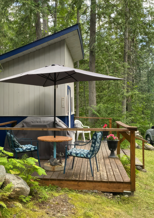 Cabin One deck with umbrella and seating surrounded by trees at Hummingbird Cabins 'n' Breakfast