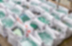 Multiple large white bags filled with cullet, waiting to be taken for recycling.